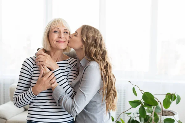 Mujer besándose madre mayor en la mejilla — Foto de Stock