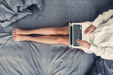 Dizüstü bilgisayar kullanarak, onun yatağında rahatlatıcı bir kadın.