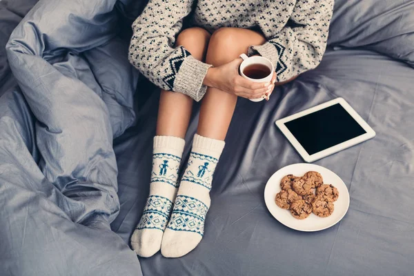 Ung kvinna njuter av mysiga tid med tablett i sängen — Stockfoto