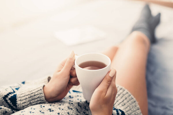 Woman resting in bed with cup of tea