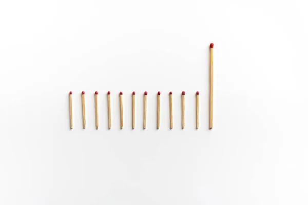 Row of matches with one big in lead on white — Stock Photo, Image