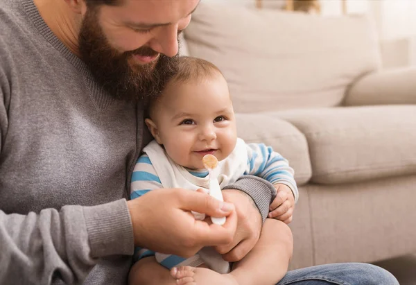Father feeding his cute baby son at home — Stock Photo, Image
