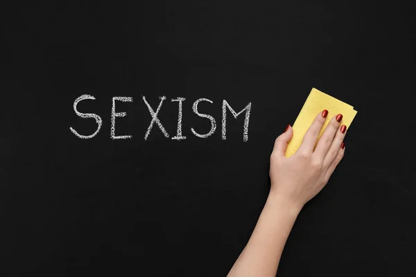 Сексизм написан на доске и руке с губкой — стоковое фото