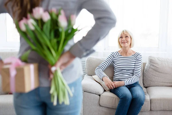 Filha escondendo tulipas e caixa de presente para sua mãe — Fotografia de Stock