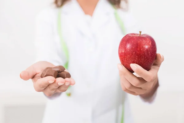 Nutricionista oferecendo maçã nutritiva como alternativa ao chocolate — Fotografia de Stock
