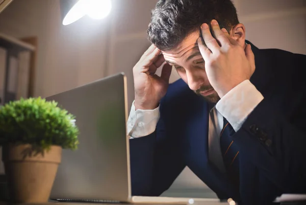 Müder männlicher Arbeiter mit Kopfschmerzen, der auf Laptop schaut — Stockfoto