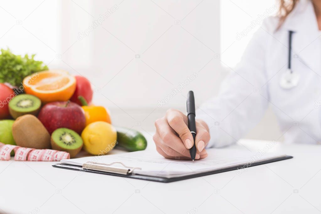 Doctor nutritionist writing on paperwork in office