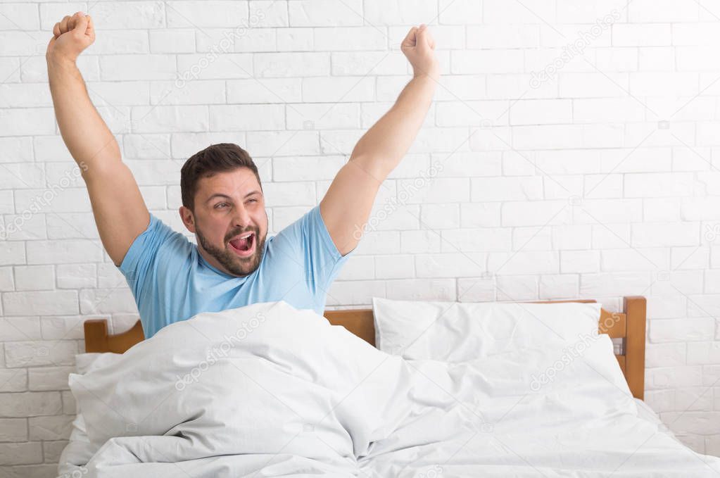 Man waking up in morning, stretching and yawning