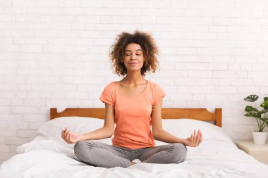 Meditasyon. Lotus poz yatakta oturan kadın