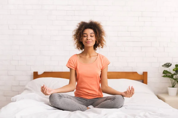 Медитация. Женщина сидит в позе лотоса на кровати — стоковое фото