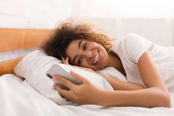 Chica feliz mensajes de texto en el teléfono inteligente en la cama —  Fotos de Stock