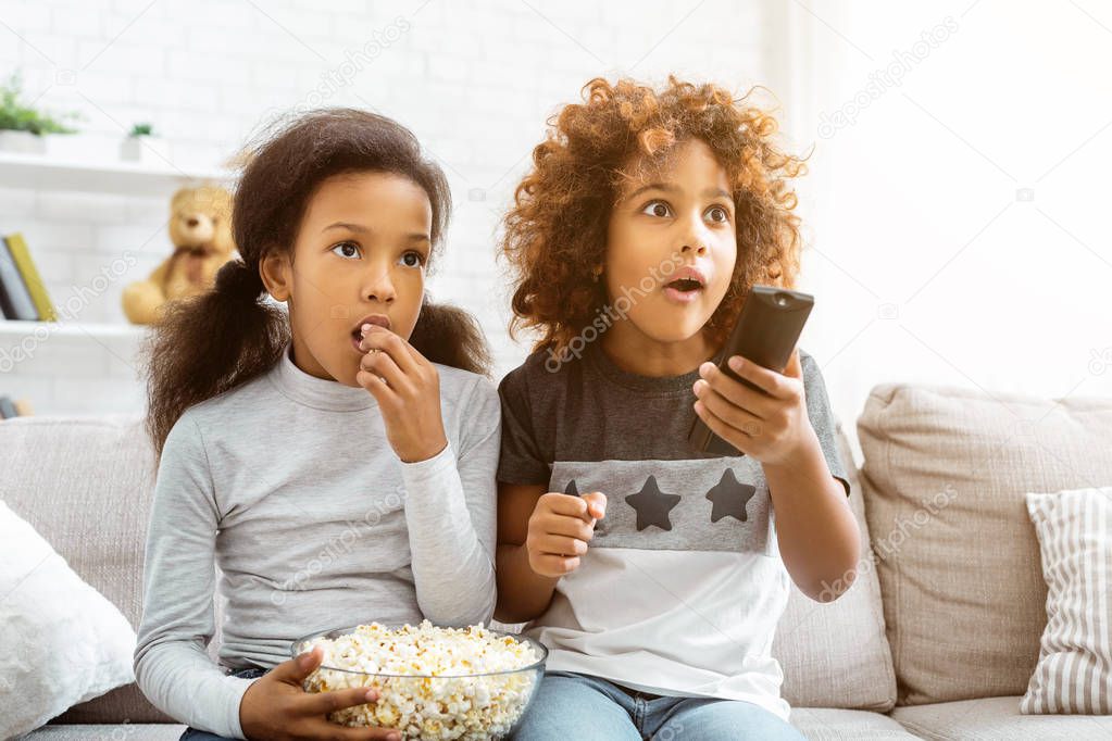 Little girls watching discovery channel and eating popcorn