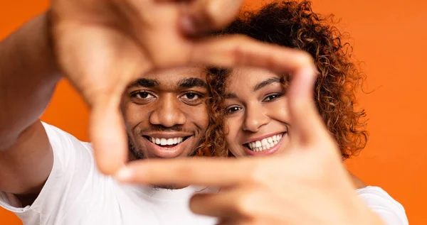 Black man and woman show frame sign with hands