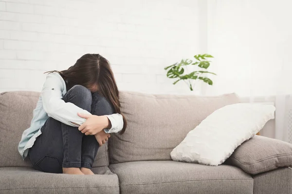 Unhappy girl sitting on sofa feeling lonely — Stock Photo, Image