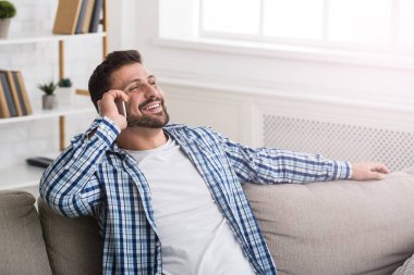 Yakışıklı adam kanepede cep telefonunda konuşuyor