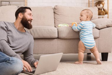 Dizüstü bilgisayarda çalışan ve onun bebek oğlu dikkat çekici genç baba