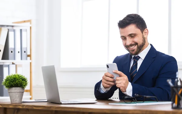 Texting aan collega. Man met smartphone, werken in office — Stockfoto