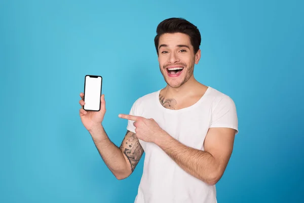 Guy pointing on smartphone with blank screen — Stock Photo, Image