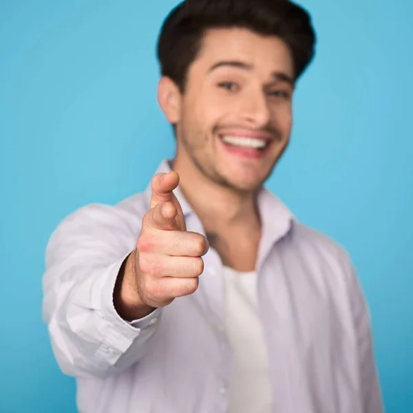 Uomo che punta il dito contro la fotocamera su sfondo blu — Foto Stock