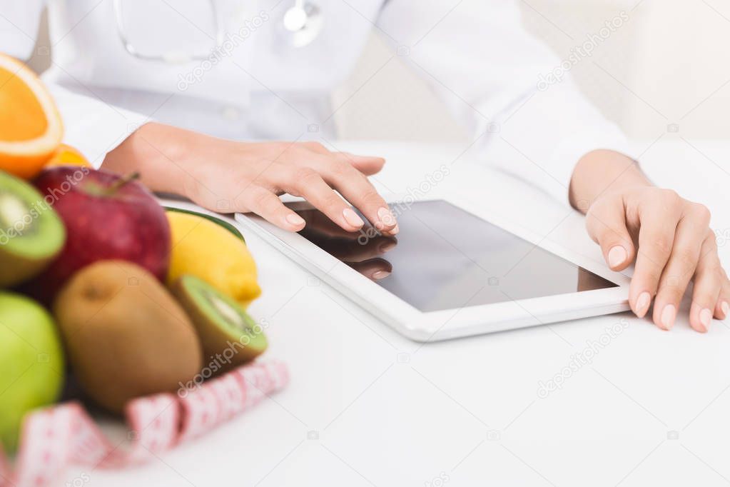 Female nutritionist hands working on digital tablet in office