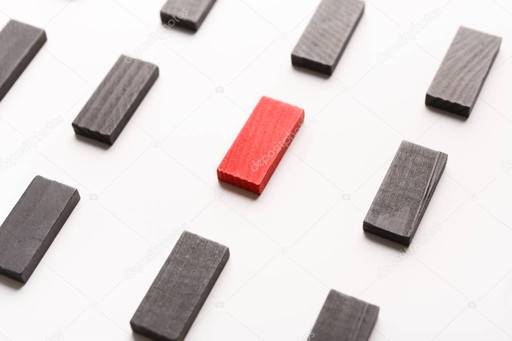 Red wooden block standing between black ones
