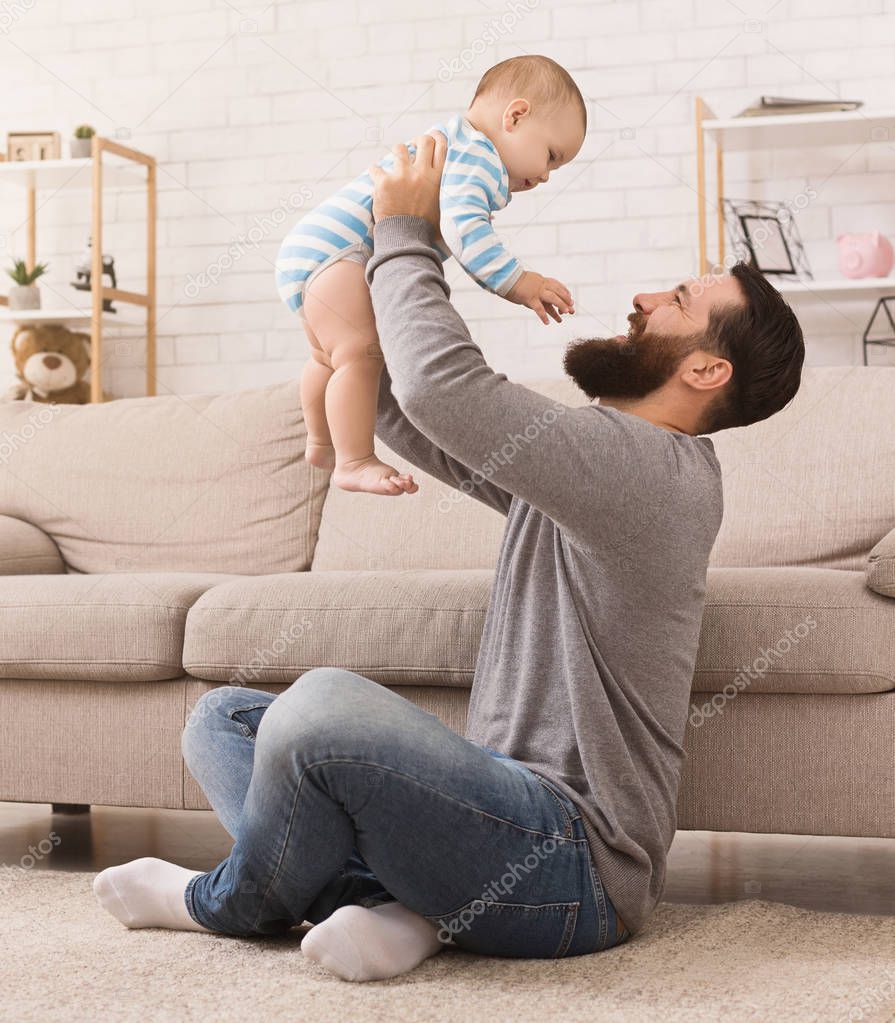 Man throwing up his son at home in living room
