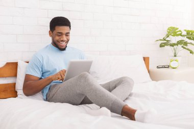 Genç bin yıllık adam yatakta dijital tablet kullanma