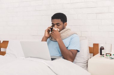 Genç hasta siyah adam yatakta laptop çalışma