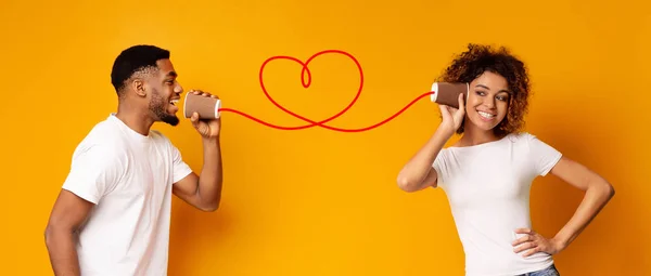 Jovem casal preto com pode telefone no fundo laranja — Fotografia de Stock