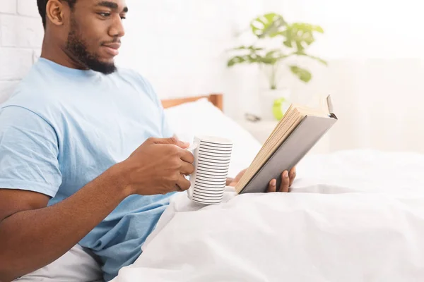 Junger schwarzer Kerl liest Buch im Bett — Stockfoto