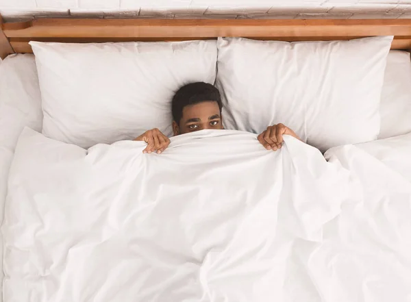 Афро-американец в постели прячется под одеялом — стоковое фото