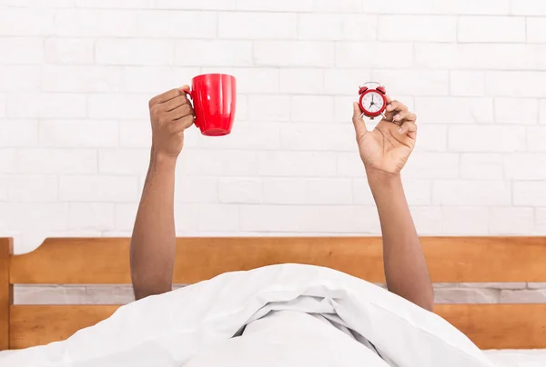 Мужская рука подняла чашку кофе в постели — стоковое фото