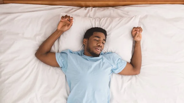 Junger afrikanisch-amerikanischer Mann schläft im Bett Draufsicht — Stockfoto