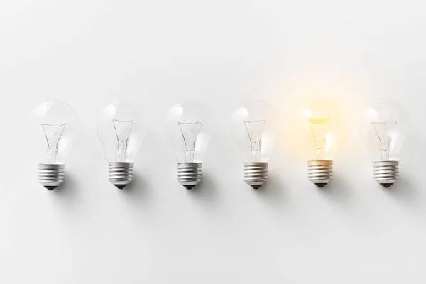 Illuminated light bulb in row of dim ones — Stock Photo, Image