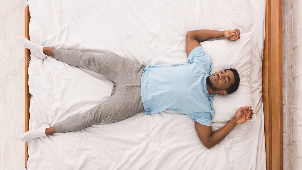 Young african-american man sleeping in bed top view