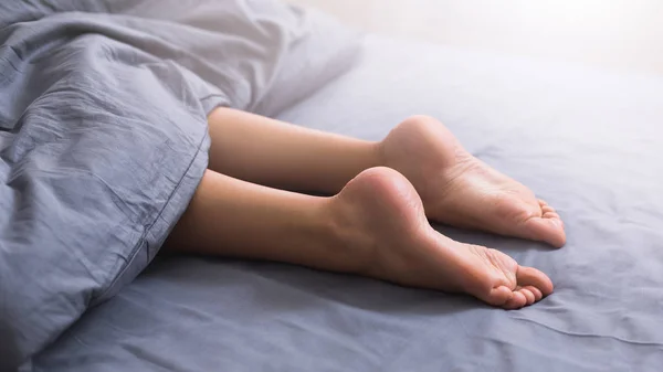 Wanita cantik kaki di bawah selimut di tempat tidur — Stok Foto