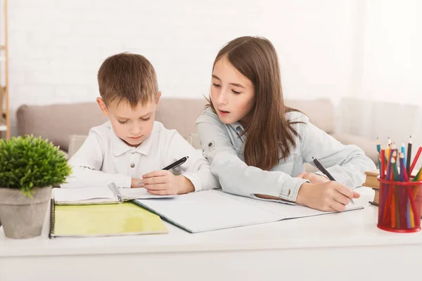 Lära sig hemma. Syster att hjälpa bror göra läxor — Stockfoto