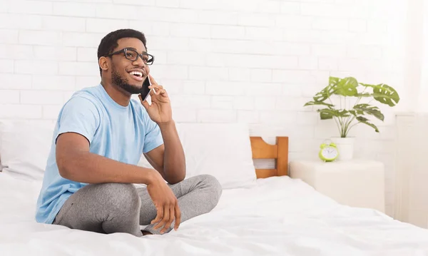Neşeli Afrikalı-Amerikalı adam yatakta telefonda bahsediyoruz — Stok fotoğraf