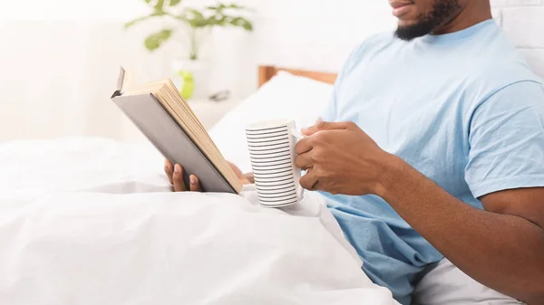 Young black guy reading book in bed — Stock Photo, Image