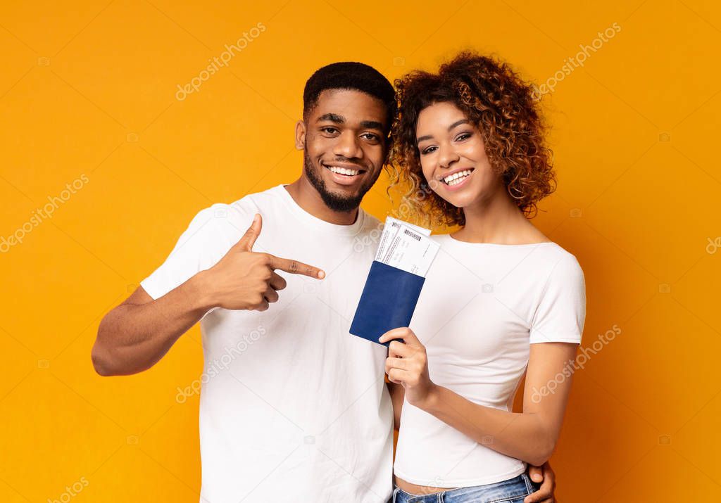 Happy young black couple holding passports and tickets