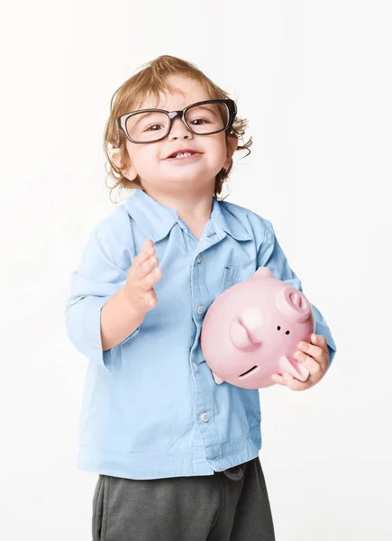 Baby boy in glasses holding pink piggybank — Stock Photo, Image