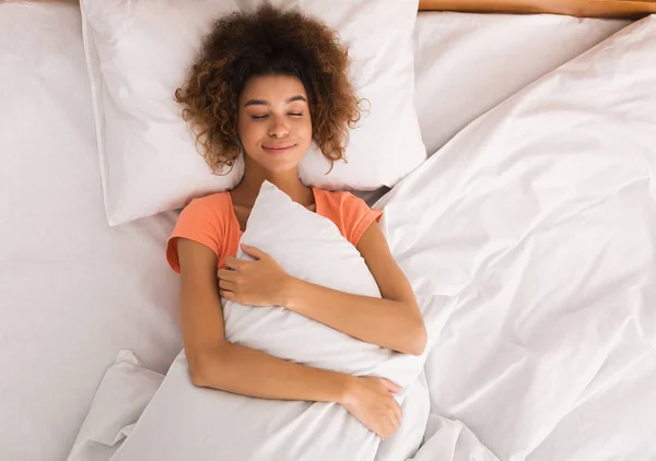 Morning time. African-american woman hugging pillow in bed — Stock Photo, Image