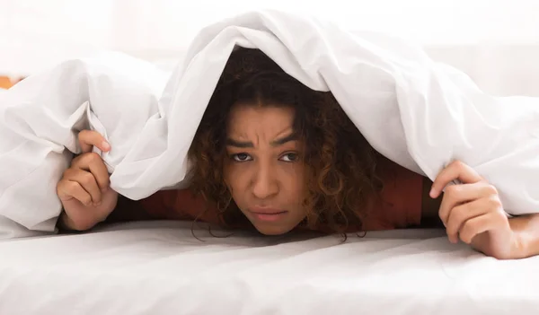 Nieszczęśliwa kobieta african-american, obejmujący koc w łóżku — Zdjęcie stockowe