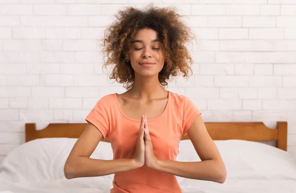 Afro-Amerikaanse vrouw in namaste yoga positie zitten en ontspannen — Stockfoto