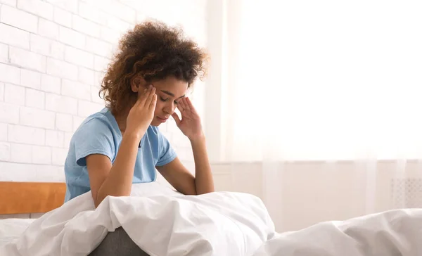 Mujer con dolor de cabeza terrible, sentada en la cama por la mañana —  Fotos de Stock
