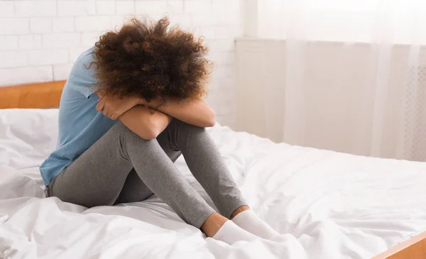 Afroamerikansk kvinna lider av depression sitter på sängen — Stockfoto