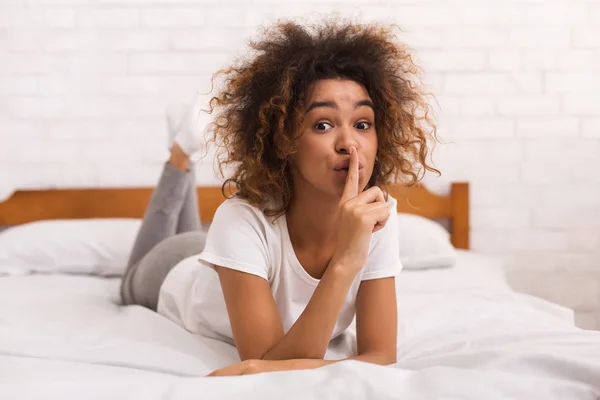 Afro-pani pokazuje gest ciszy w łóżku — Zdjęcie stockowe