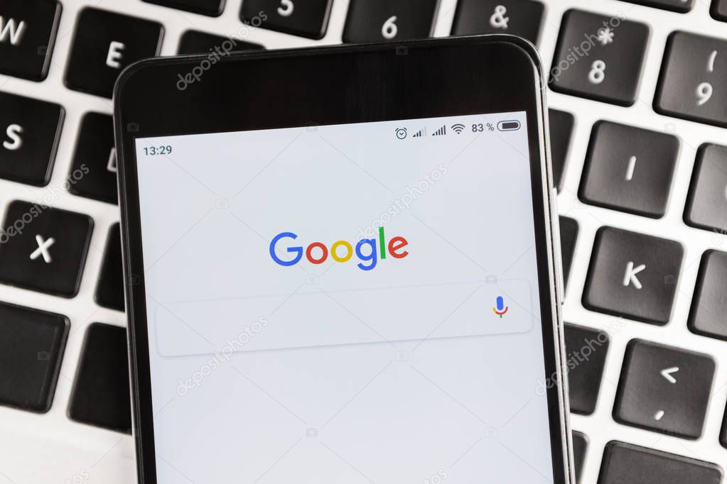 Kharkiv, Ukraine - December 11, 2018: iPhone screen with Google search application, lying on laptop keyboard. Google is the most used search engine on World Wide Web