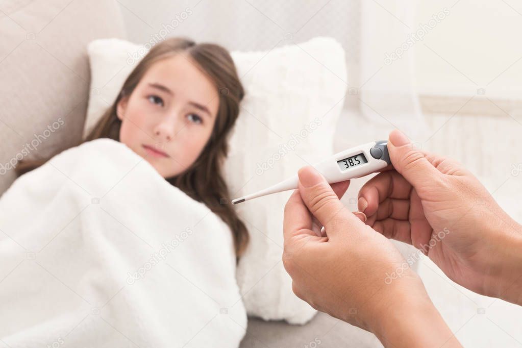 Mother measuring temperature of her ill daughter
