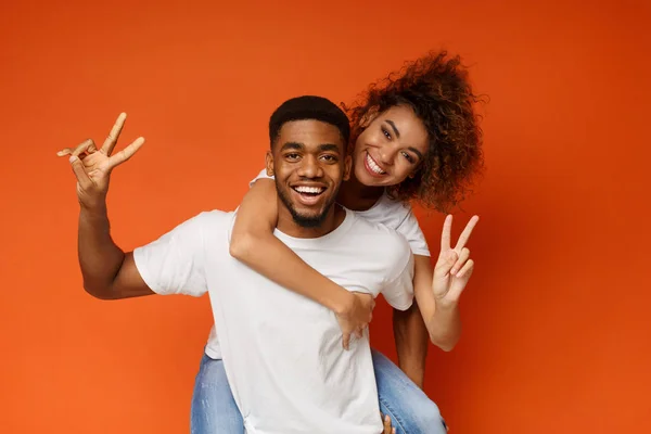 Jovem casal preto piggyback passeio, mostrando ok gesto — Fotografia de Stock